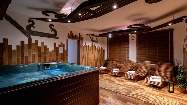 A spa area with a hot tub, wooden flooring, and lounge chairs. - Penzión Lomnicky (Stara Lesna)