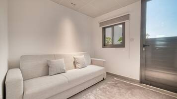 A minimalist living room with a sofa, a window, and a sliding door.