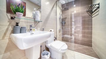 A modern bathroom with a large sink, toilet, and glass-enclosed shower.