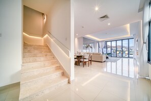 A modern interior with a staircase, a dining area, and large windows offering a view.