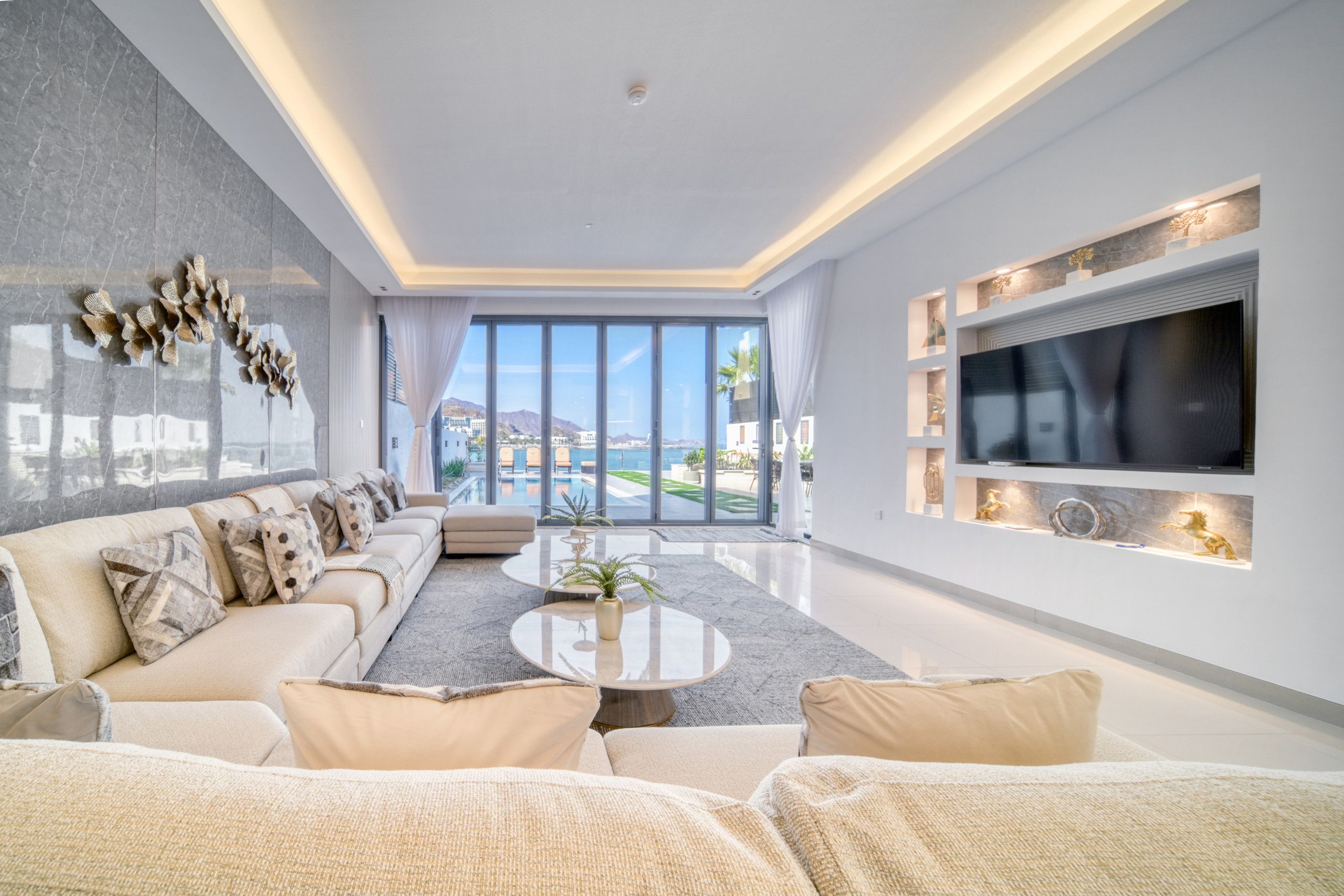 Un salon moderne avec un canapé, une table basse et un téléviseur fixé au mur.