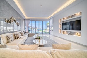 A modern living room with a sofa, coffee table, and a TV mounted on the wall.