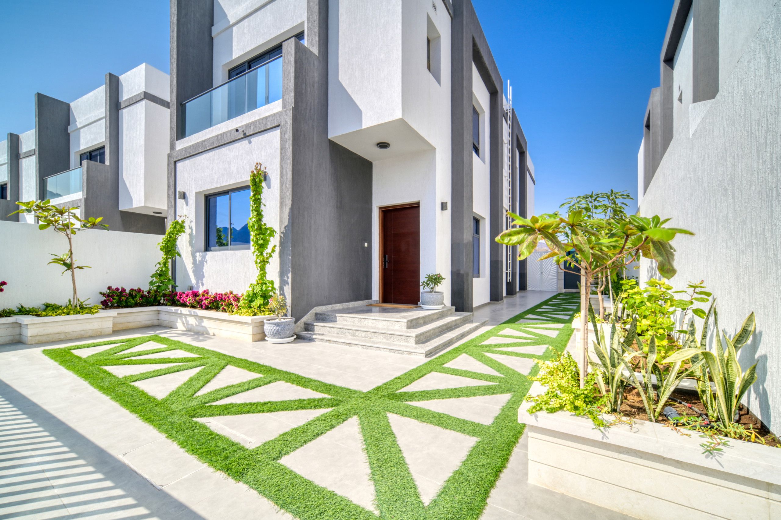 A modern two-story residential building with a symmetrical facade, large windows, and a central entrance.