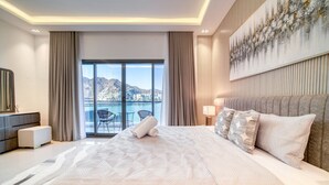 A modern hotel room with a large bed, a view of the sea, and a balcony.