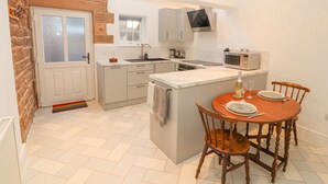 A modern kitchen with a large island, white cabinets, and a built-in microwave. - Hillside Hideaway (Wigton)