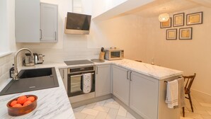 A modern kitchen with grey cabinets, a built-in oven, a microwave, and a sink. - Hillside Hideaway (Wigton)