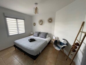 A bedroom with a bed, bedside tables, a chair, and a ladder. - T3 Spacieux les 3 Ilets Vue Mer (Les Trois-Îlets)