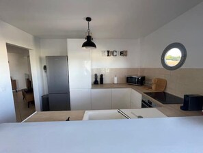 Een moderne keuken met witte kasten, een roestvrijstalen koelkast, een magnetron en een houten aanrecht.