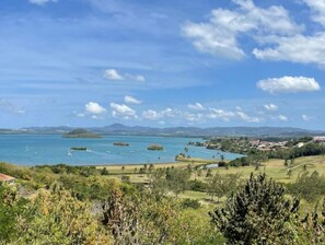 A coastal landscape with a clear sky, a body of water, and distant hills. - T3 Spacieux les 3 Ilets Vue Mer (Les Trois-Îlets)