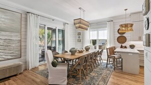 Un vaste espace dédié à la salle à manger, avec une table en bois, des chaises en osier et un grand tapis.