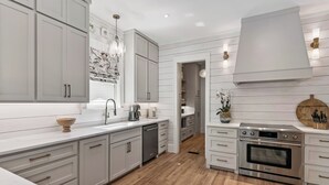 Une cuisine moderne avec des meubles blancs, un four en acier inoxydable et un plancher en bois.