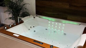 Ein modernes Badezimmer mit einem Holzkosmetikschrank, einer großzügigen Badewanne und einem Blumentopf.