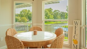 A round table with wicker chairs and a "WELCOME" sign, overlooking a scenic view with a balcony and railing. - Waterfront with Boat Slip, Sports Bar, SUP'S, Great Location! (Willis)