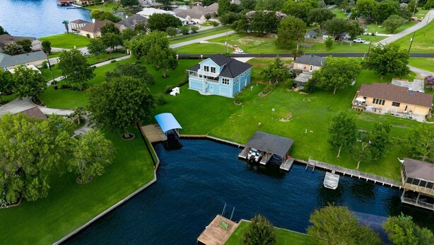 A residential area with a large house featuring a dock and a small boat. - Waterfront with Boat Slip, Sports Bar, SUP'S, Great Location! (Willis)