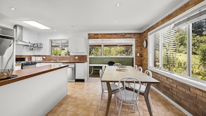 Una cocina moderna con armarios blancos, encimera de madera y un comedor con mesa y sillas.