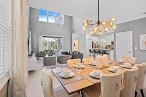 A dining area with a wooden table set for four, surrounded by upholstered chairs. - 5BR Home w/ Game & Themed Rooms at Champions Gate (Kissimmee)