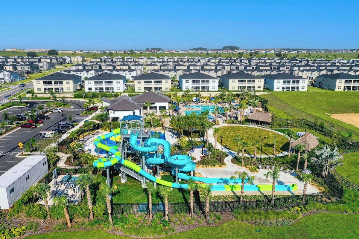 A residential area with a water park, including slides and pools, surrounded by houses.