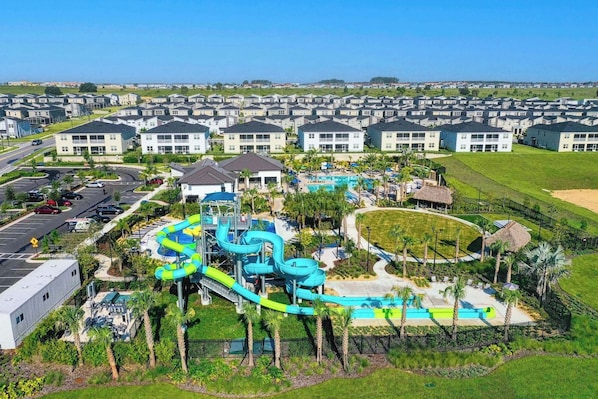 A residential area with a water park, including slides and pools, surrounded by houses.