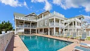 A large, multi-story building with a swimming pool and outdoor seating area. - Crew Quarters -- 16BR Oceanfront with Elevator, Pool and More! (Corolla)