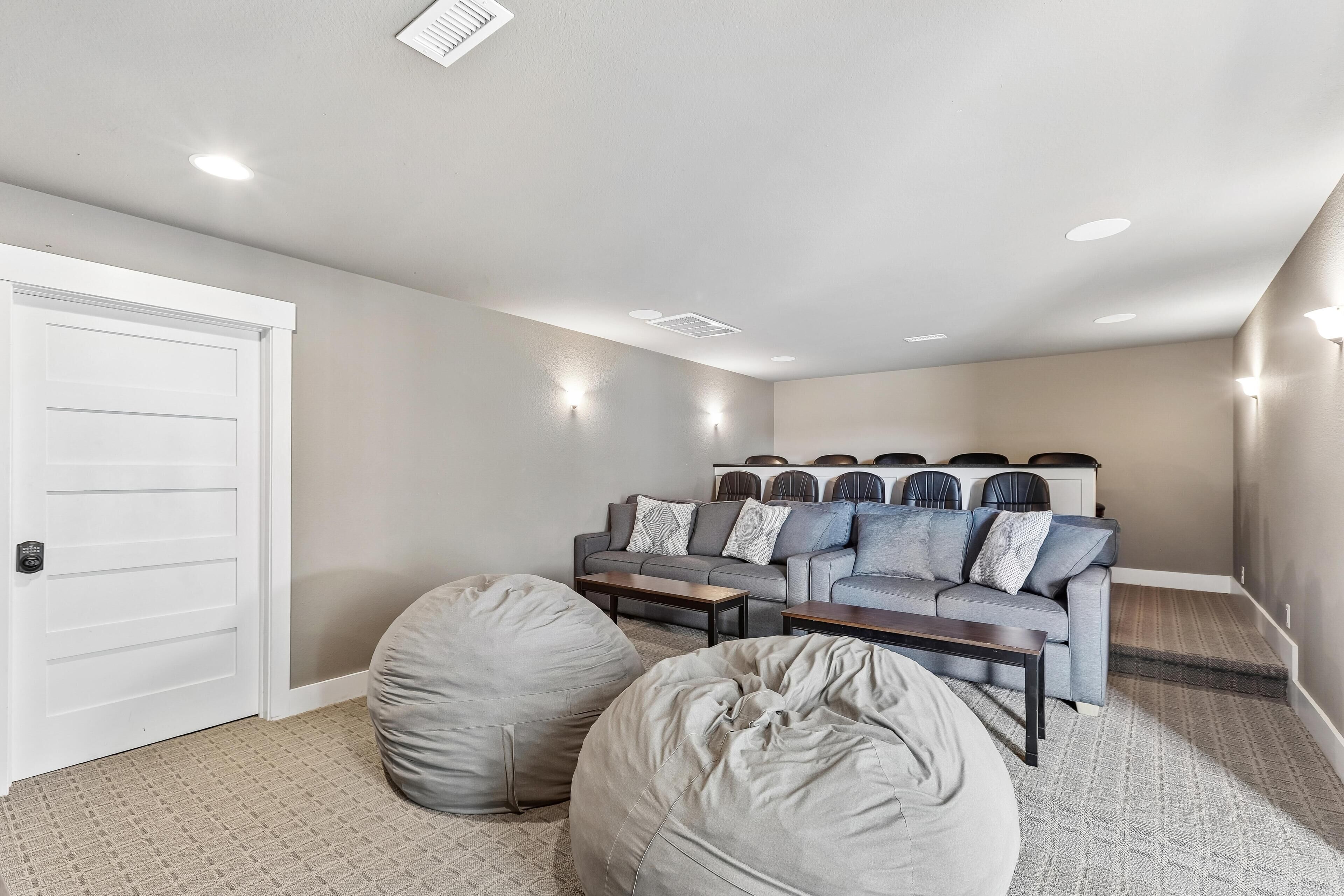 Ein Heimkinozimmer mit grauem Sofa, Sitzsäcken und einer weißen Tür.