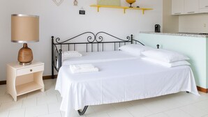 A neatly made bed with white linens, a bedside table with a lamp, and a small shelf above the bed. - VivimiHome–Mare e relax nel cuore di Porto Rotondo (olbia)