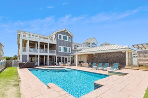 A two-story house with a swimming pool, outdoor seating, and a covered patio area.