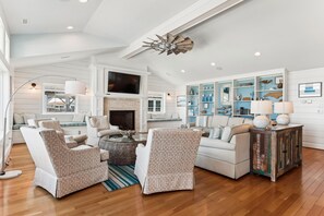 A spacious living room with a fireplace, comfortable seating, and a large entertainment unit.