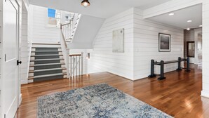 Ein geräumiger Flur mit Holzboden, einer Treppe mit gemustertem Teppich und einer Wandleuchte.