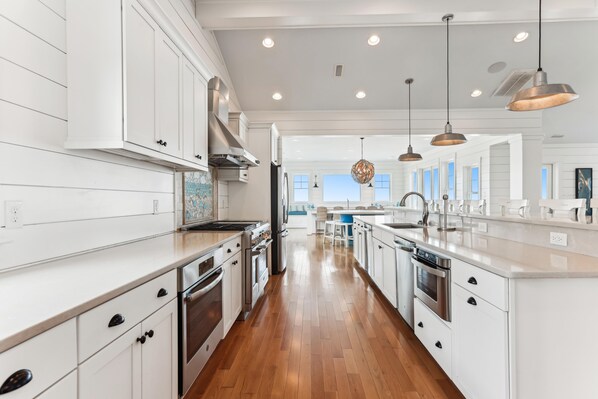 A modern kitchen with white cabinetry, stainless steel appliances, and a central island. - Knot Home -- 16BR OF in Corolla with Pool, Elevator, Theater, Game Room and More! (Corolla)