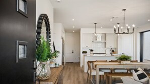 A modern kitchen with white cabinets, a wooden dining table, and a chandelier. - The Beach Club: Desert Color Lagoon + Beaches (St. George)