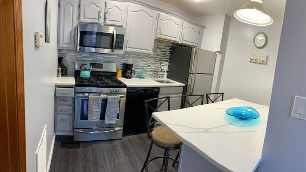 A modern kitchen with white cabinets, stainless steel appliances, and a blue bowl on the counter.