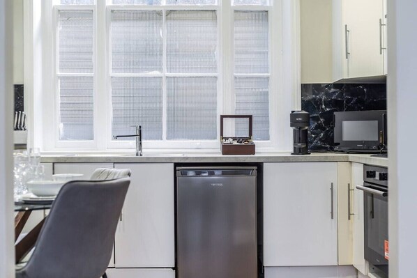 A modern kitchen with a dishwasher, a microwave, and a coffee maker on the countertop.