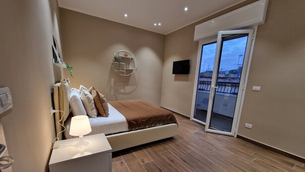 A modern bedroom with a bed, bedside table, and a wall-mounted TV. - PICCOLE DONNE (Naples)