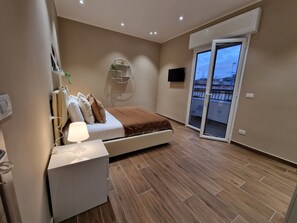 Une chambre à coucher moderne avec un lit, une table de chevet et un téléviseur fixé au mur.