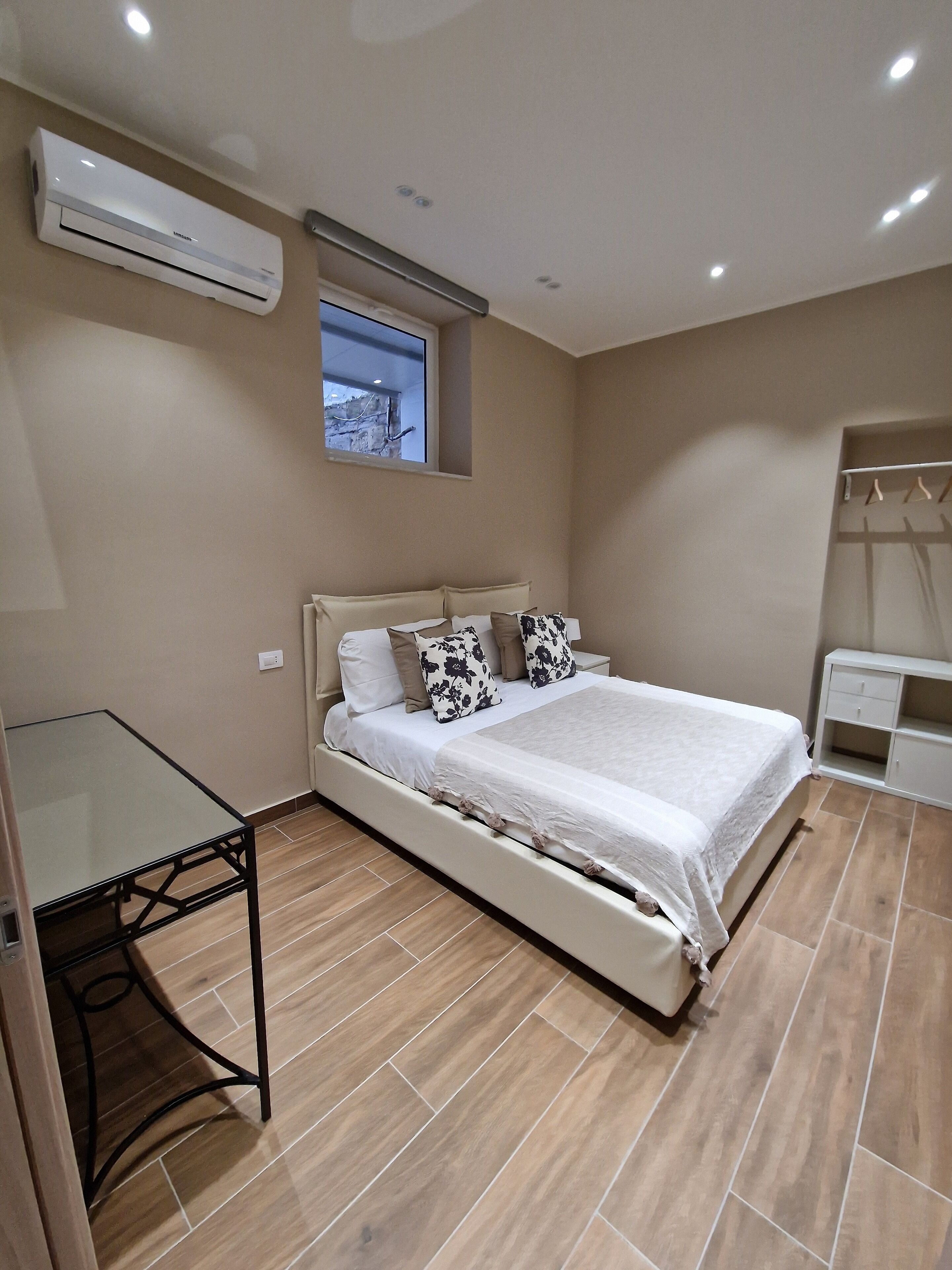 Quarto com cama, escrivaninha e ar condicionado.