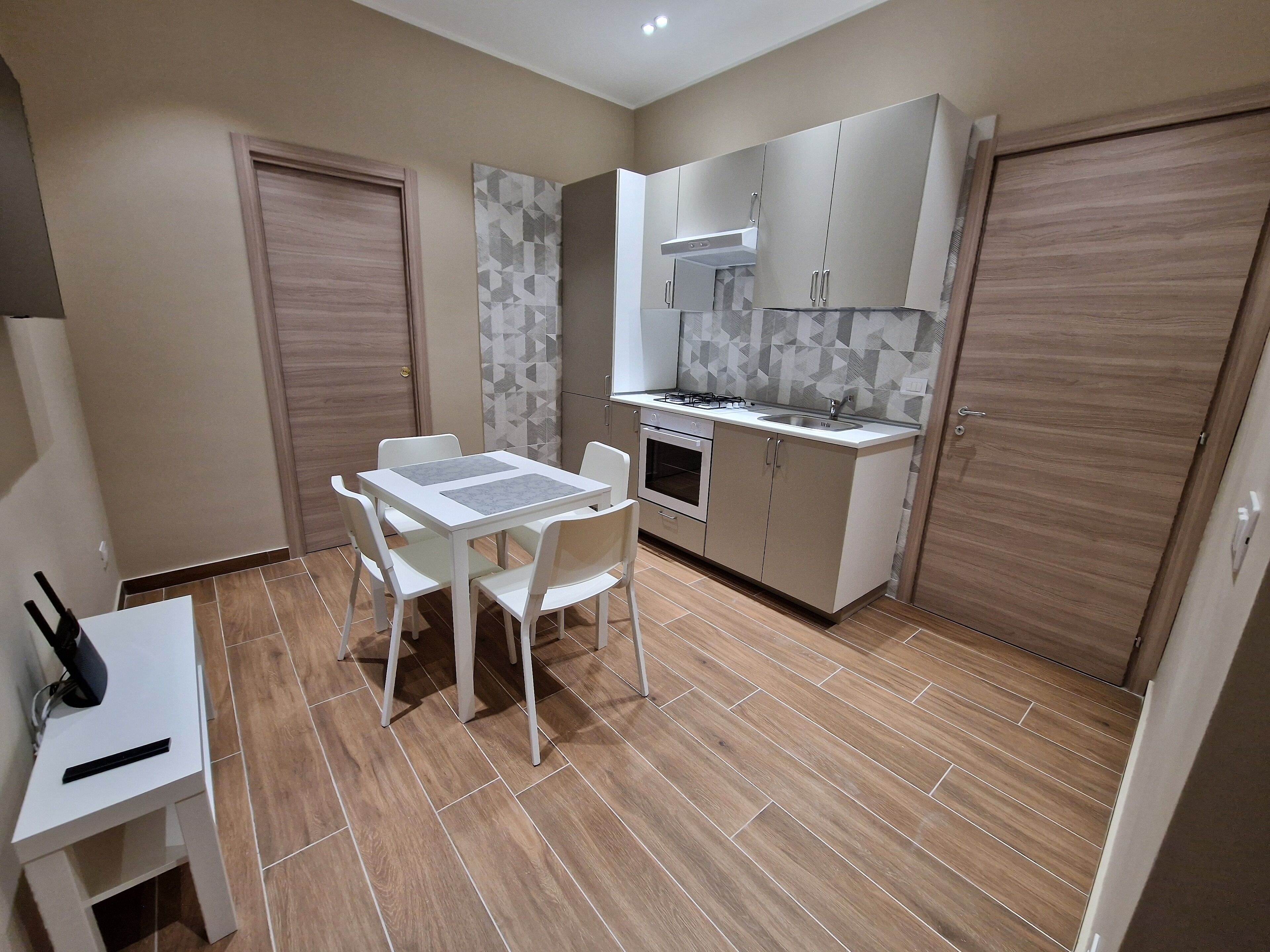 Une cuisine compacte comprenant une table et des chaises, un four encastré et un évier.