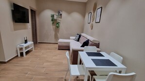 A modern living room with a sofa, dining table, and chairs. - PICCOLE DONNE (Naples)