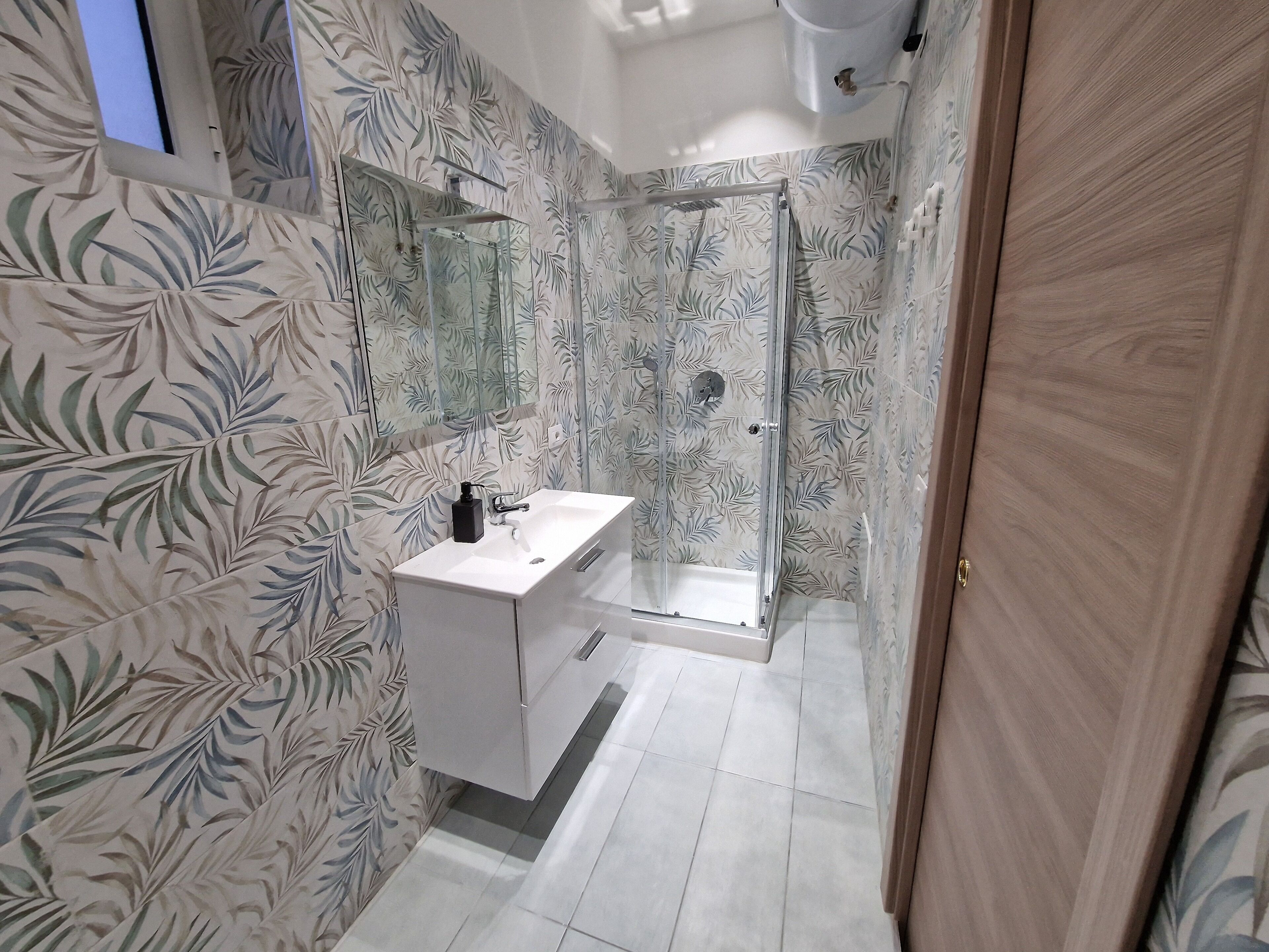 A modern bathroom with a shower, a sink, and a mirror.