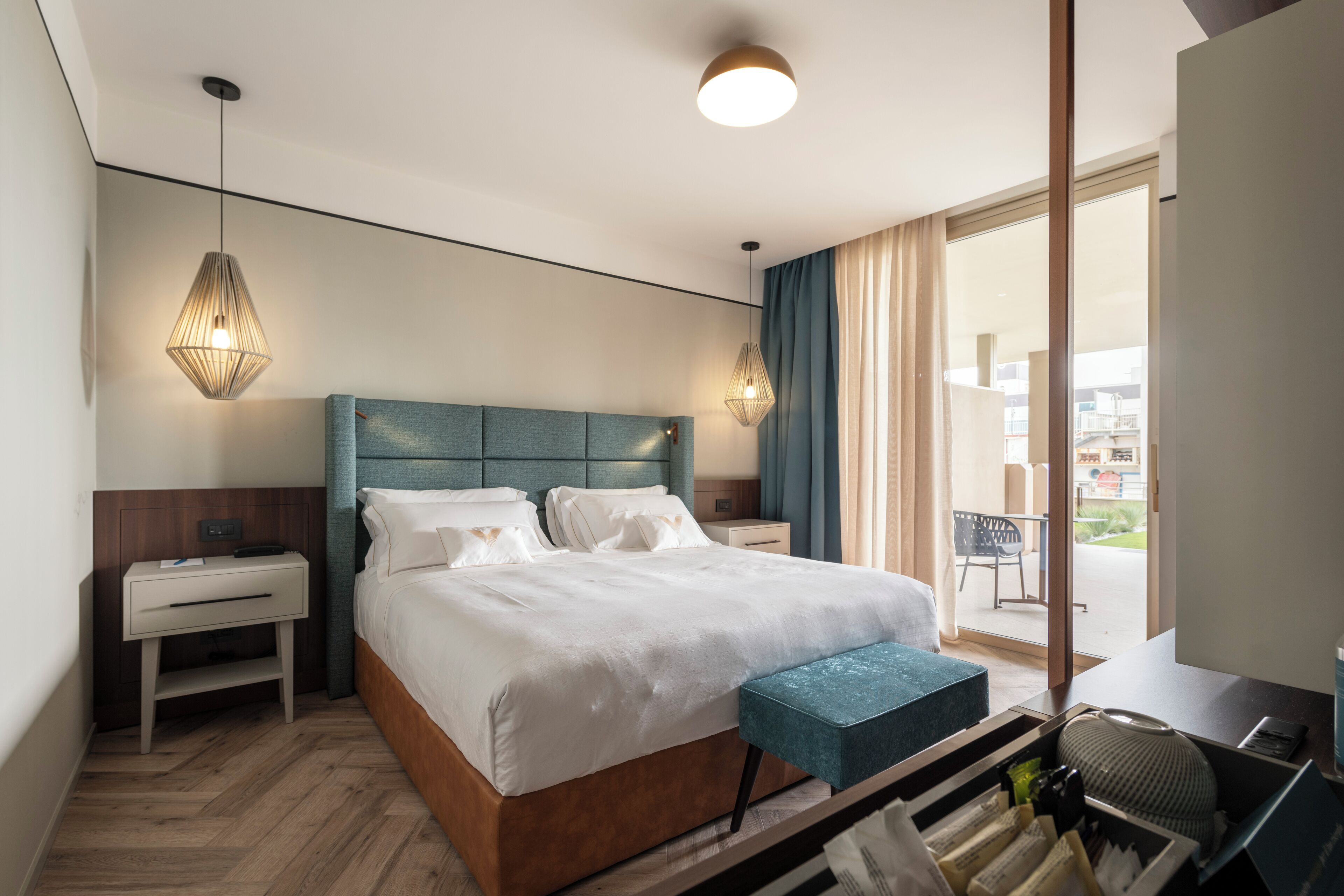 Moderni hotellihuone, jossa on suuri sänky, yöpöydät, työpöytä ja näkymä ulos.