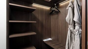 A walk-in closet with wooden shelves, a bench, and a robe hanging on a hanger.