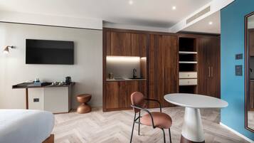 Camera d'albergo moderna con armadio in legno, televisore a schermo piatto, tavolo da pranzo e un letto.