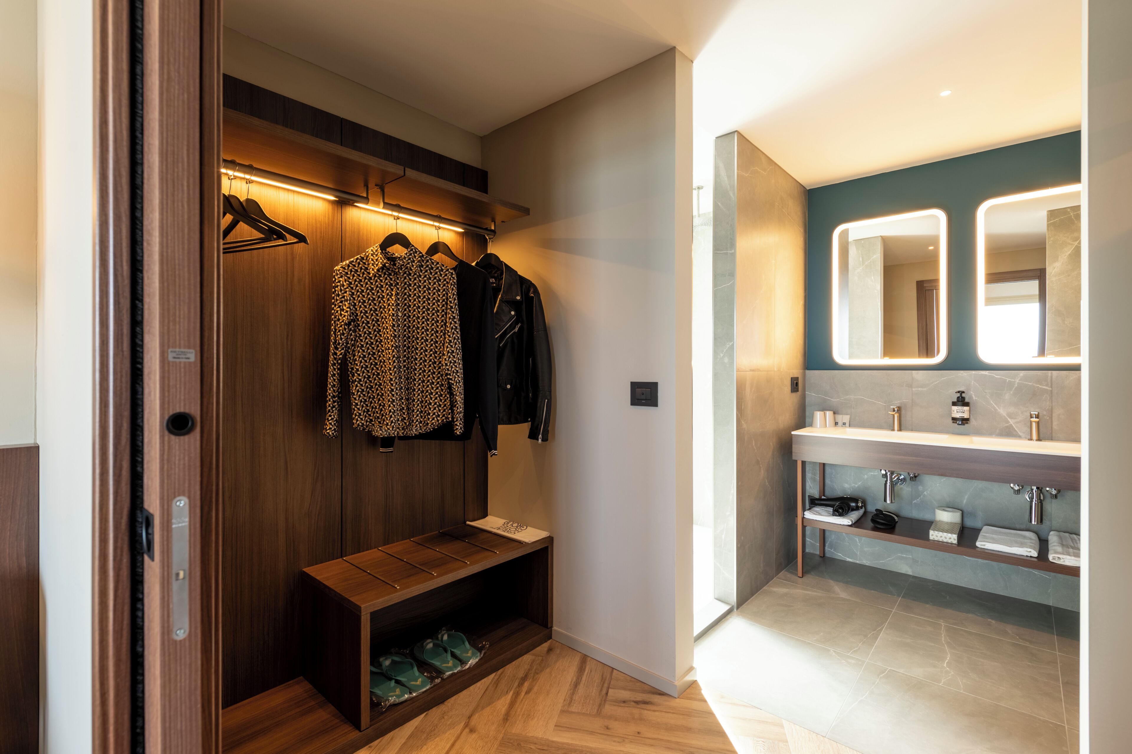 Un baño moderno con tocador, espejo y un banco de madera con zapatos.