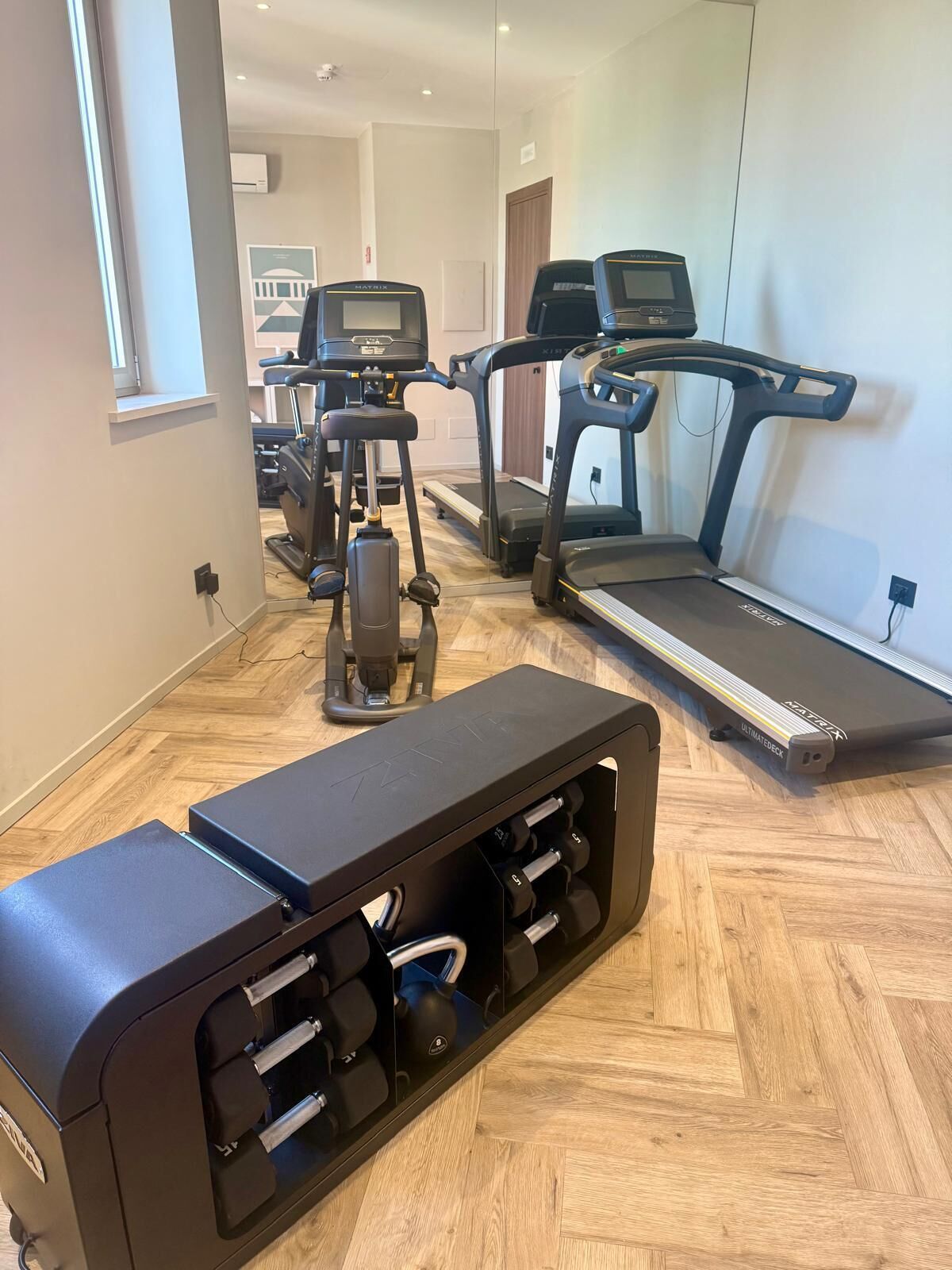 A home gym with a treadmill, elliptical, and weight bench.