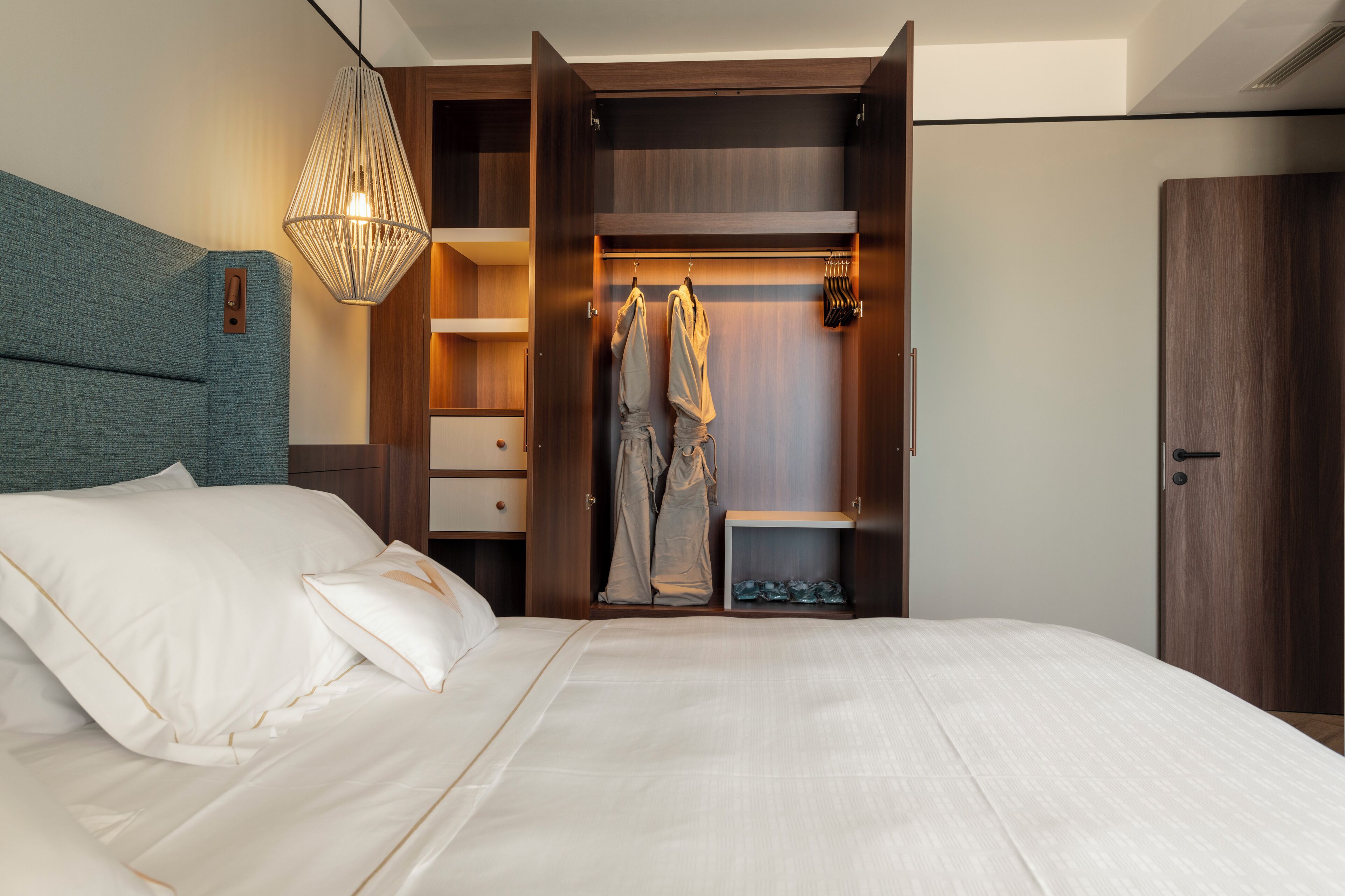 Ein Schlafzimmer mit einem großen Bett, einem Kleiderschrank mit Ablagefläche und einer Pendelleuchte.