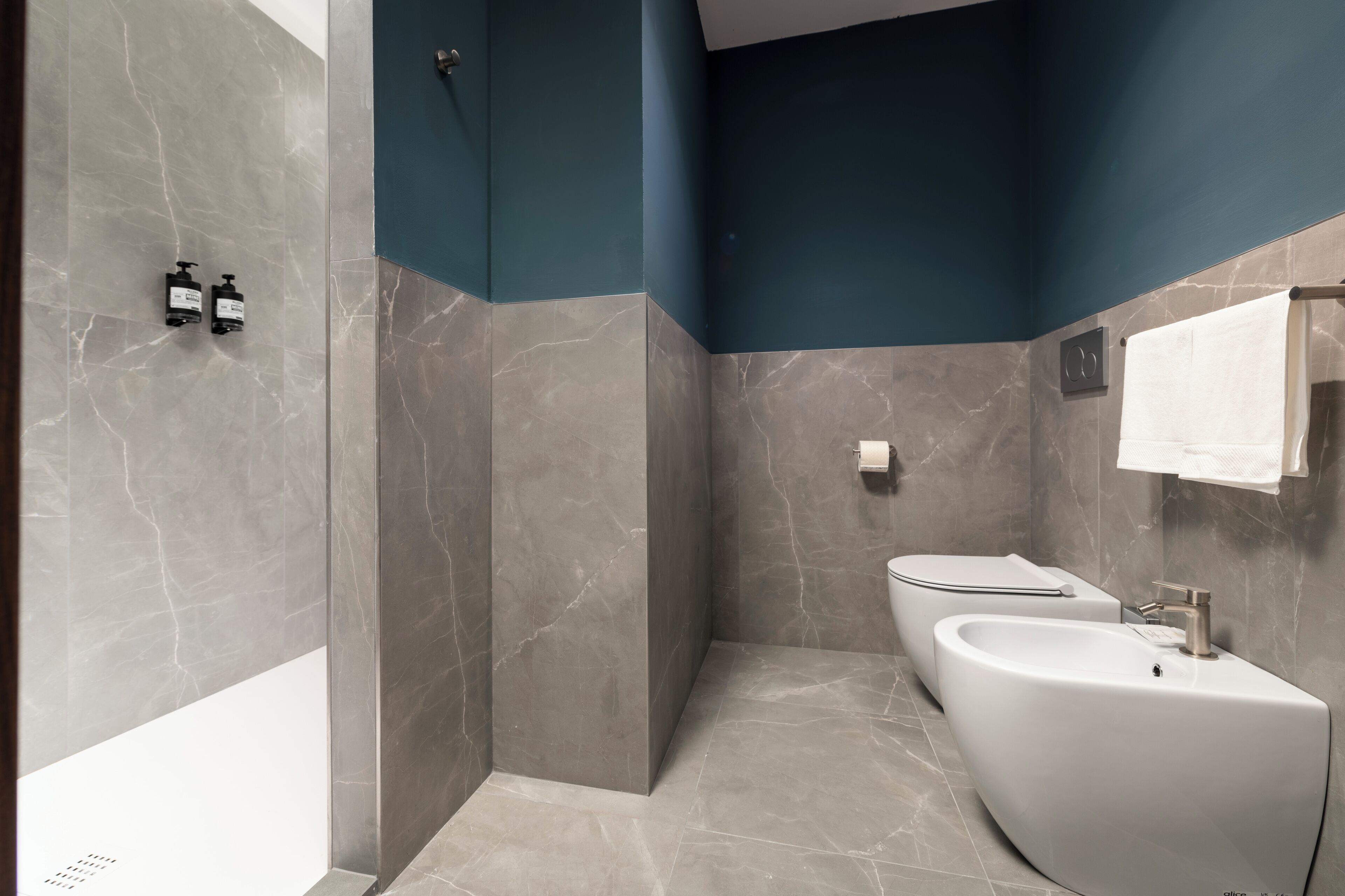 Une salle de bain moderne avec un lavabo aux lignes courbes, un porte-serviettes et un espace douche.