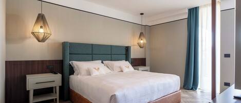 Quarto de hotel moderno com uma cama grande, duas mesas de cabeceira e um criado-mudo.