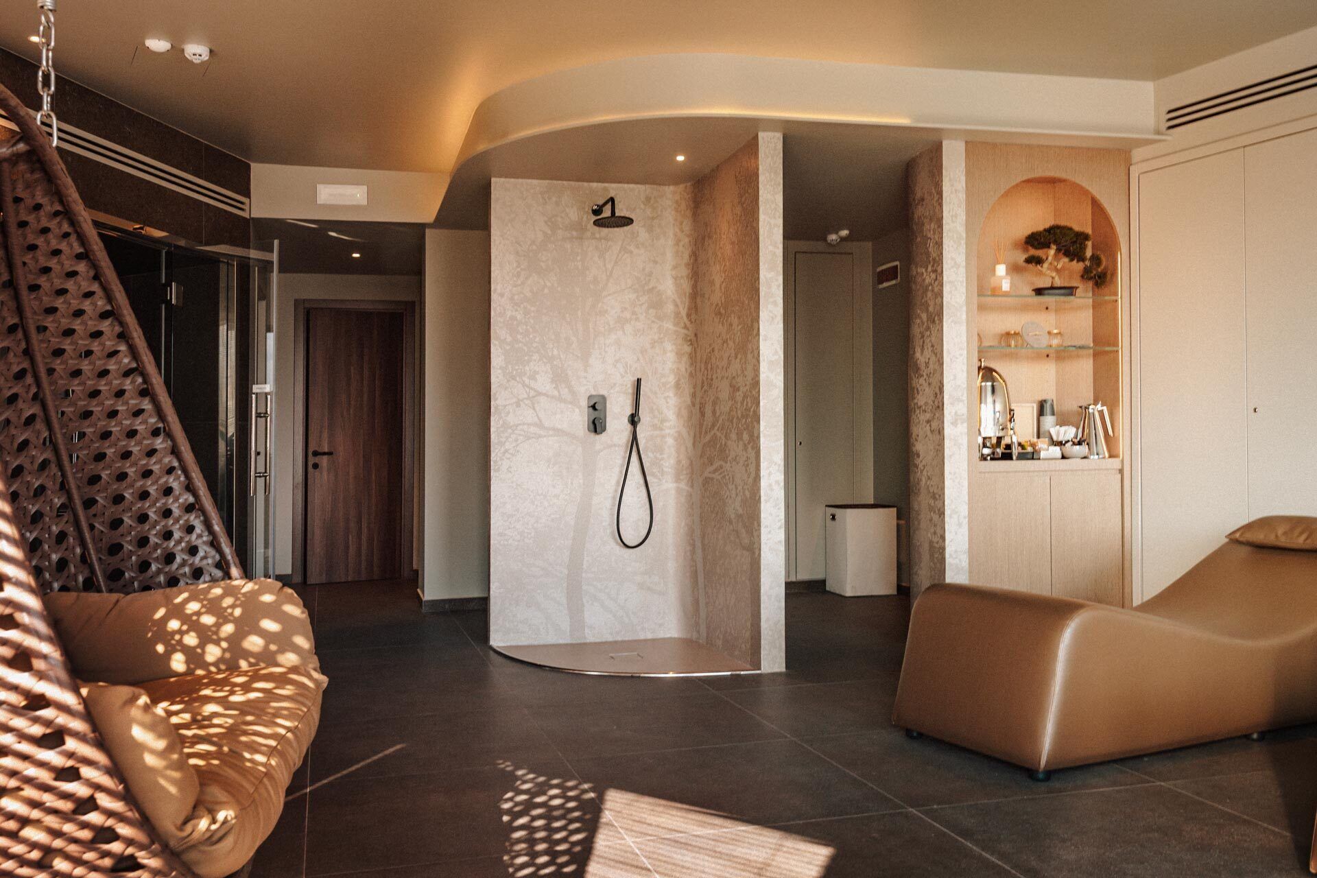 Een moderne badkamer met een inloopdouche, een zithoek met een hangmat en een wastafel met spiegel en planken.