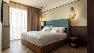 Ein modernes Hotelzimmer mit einem großen Bett, Holzboden, einem Holz-Kopfteil und zwei Pendelleuchten.