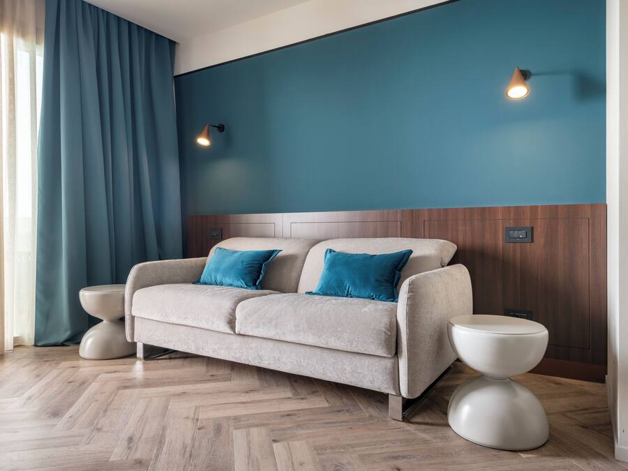 Een moderne hotelkamer met een bank, twee bijzettafels en een houten accentmuur.