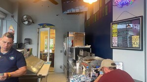 A bar with a neon sign reading "TIKI BAR OPEN", a menu board, and a counter with various items.
